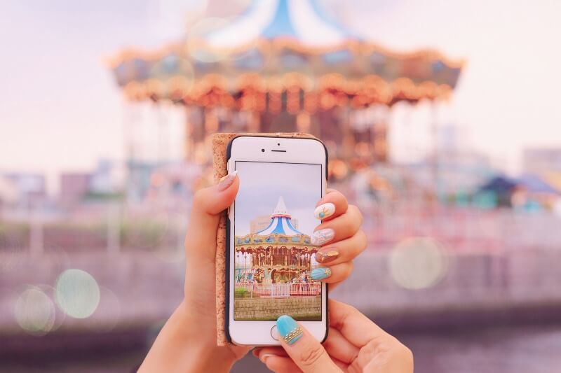 メリーゴーランドをスマホで撮る女性