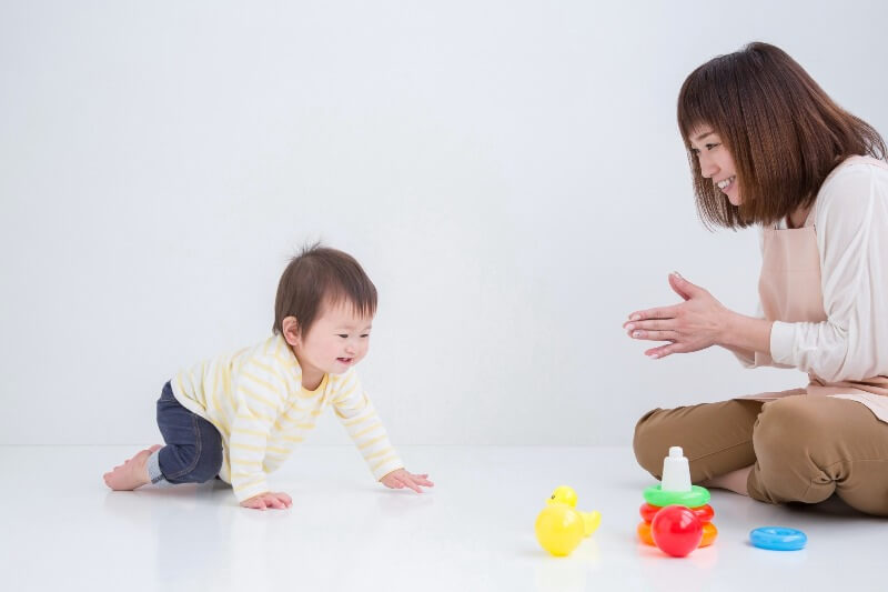 ハイハイをしている赤ちゃんを見守る保育士