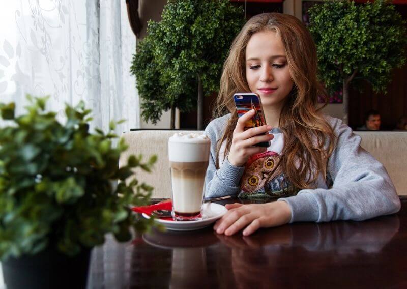 カフェラテを飲みながらスマホを触る女性