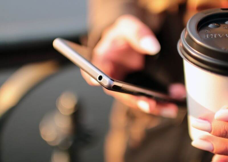 スマホを見ながらコーヒーを飲む女性